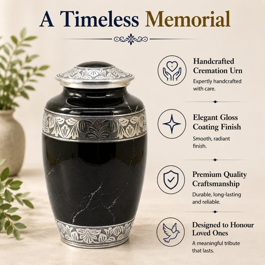 Black cremation urn with silver detailing on a light wooden surface, surrounded by greenery.