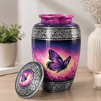 A decorative urn with a matching lid, featuring a purple and pink butterfly design on a gradient background, set on a wooden table with a potted plant and candle in the background.