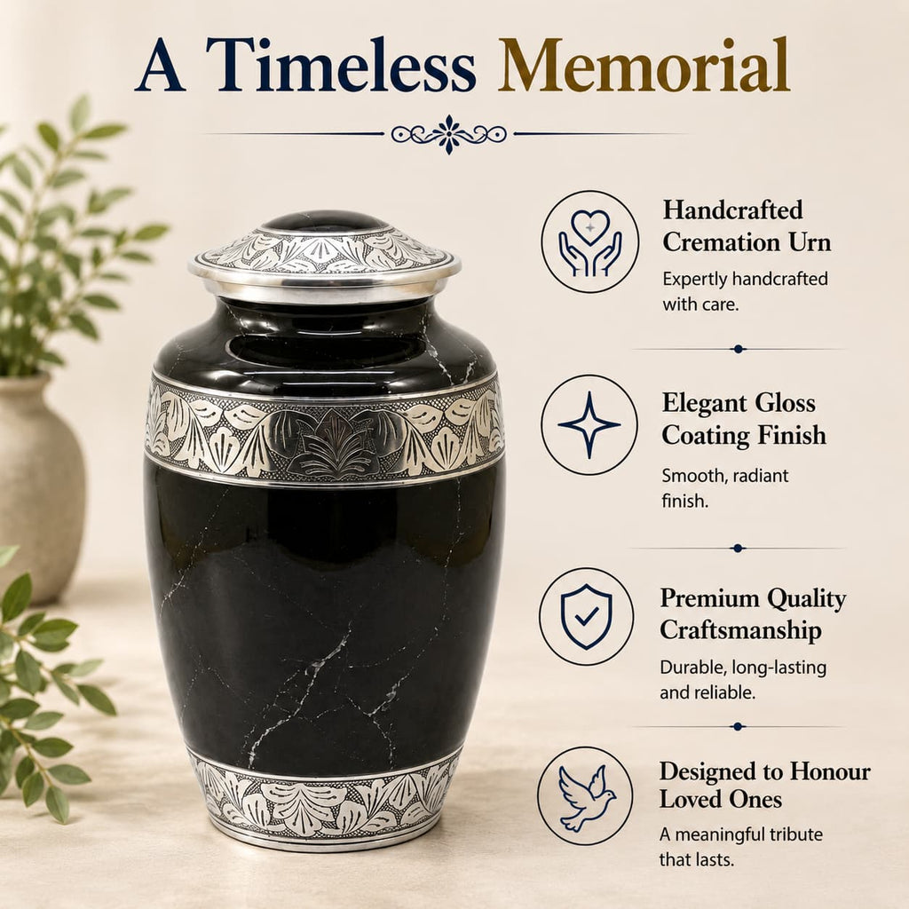 Black cremation urn with silver detailing on a light wooden surface, surrounded by greenery.