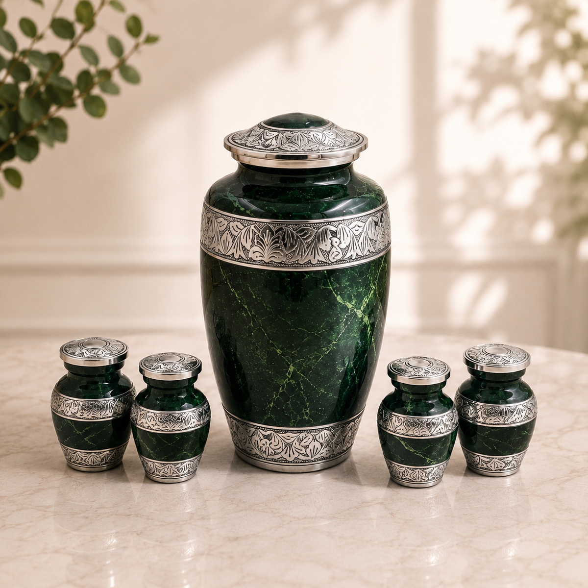A dark green marbled urn set with ornate silver metal bands and lids, displayed on a light marble surface with a softly lit indoor background.